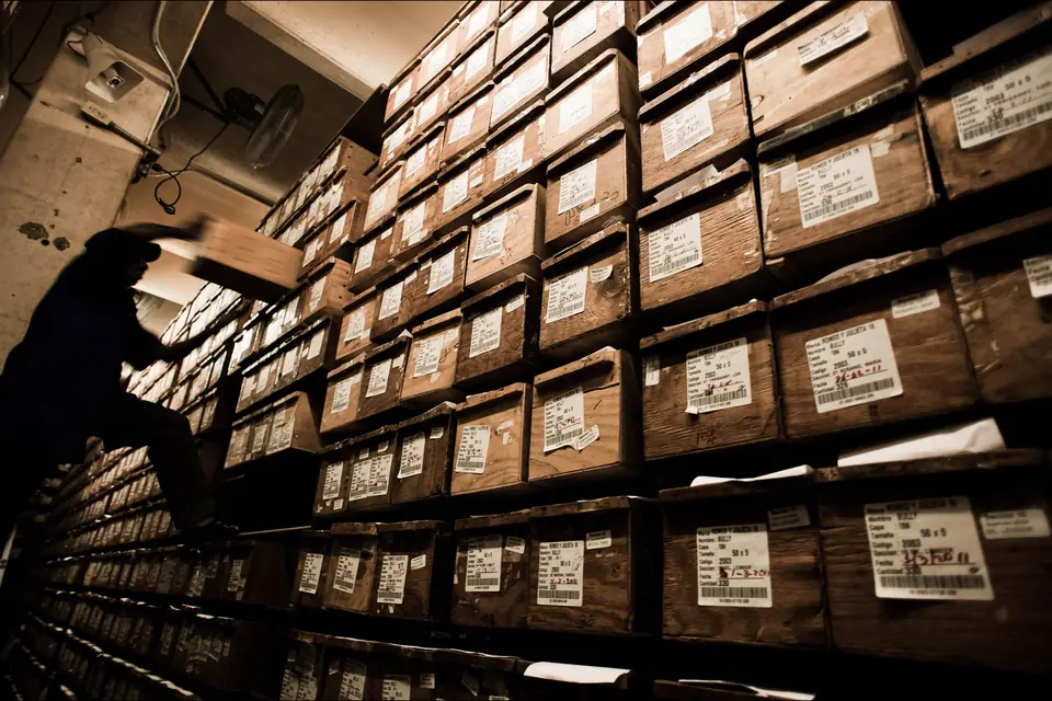 H Upmann Half Corona Review — stacked cedar cigar boxes ageing on shelves in a dark factory storeroom