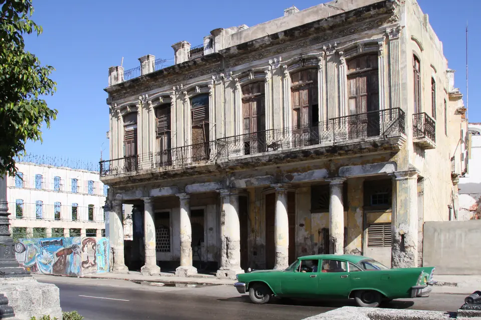 Cuban Cigars: The Complete Guide to Habanos — green classic American car passing a weathered colonial building on a Havana street