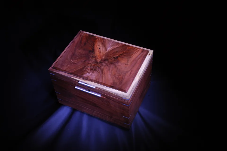 How to Store Cigars in a Tropical Climate — handmade figured-wood humidor box with closed lid, lit against a dark background